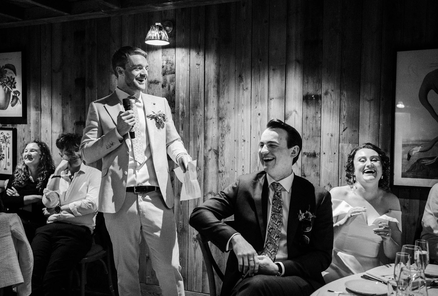 A black and white candid photograph of people laughing and having fun at what appears to be a casual gathering or party.