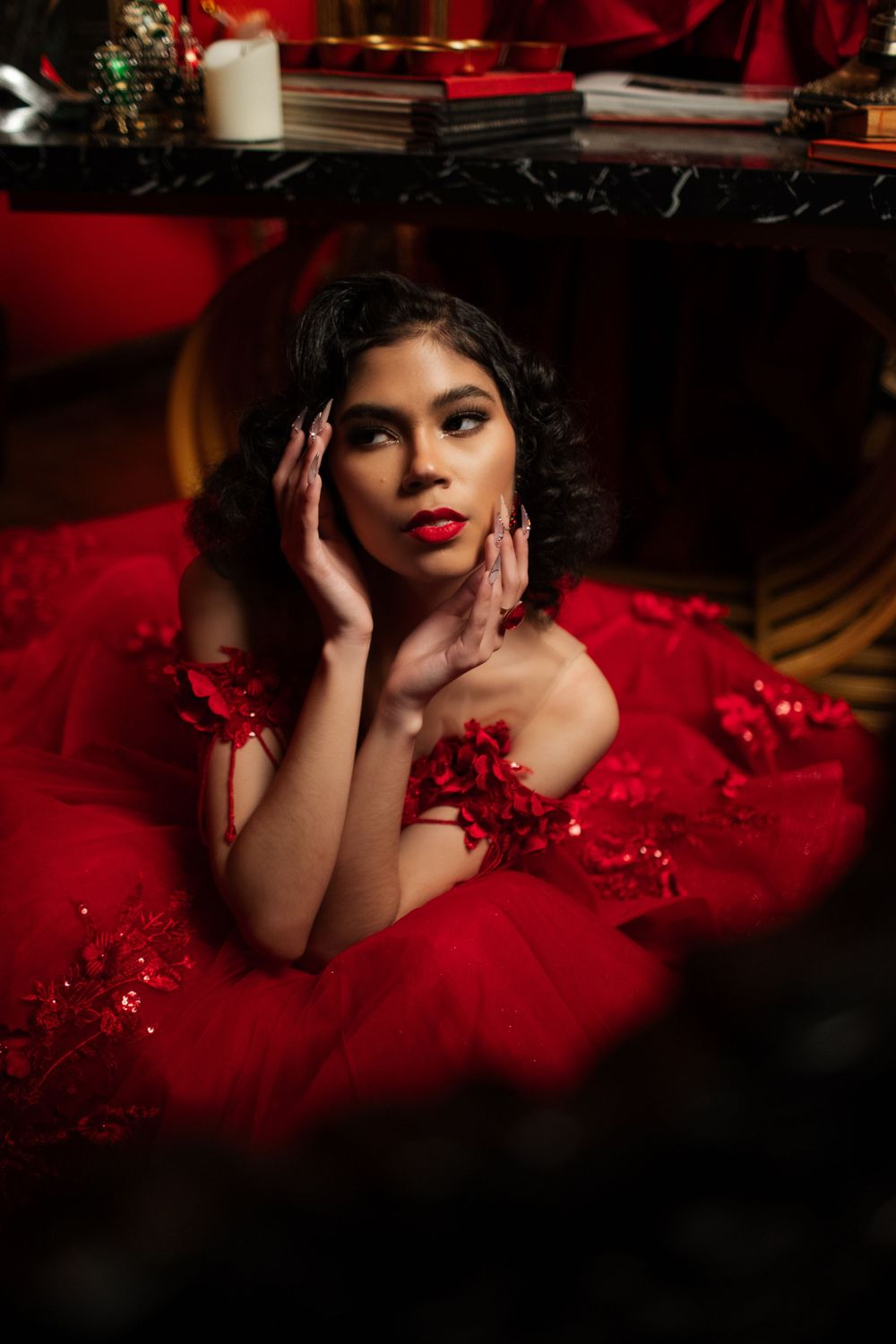 Fashion portrait in luxurious red tulle gown with dramatic lighting and romantic mood against dark background.