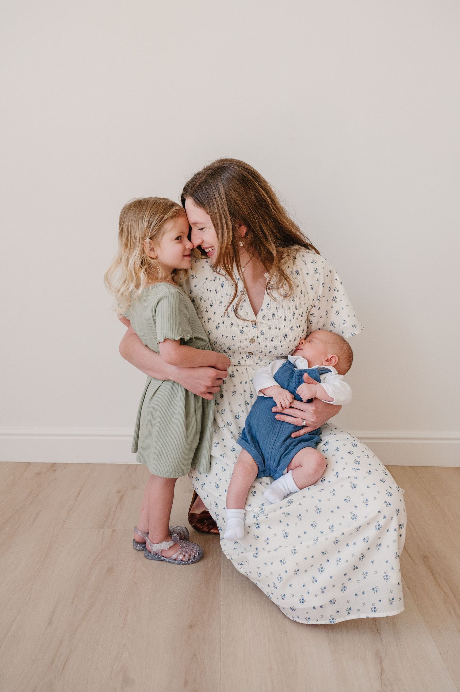 A tender family moment captured in a minimal setting with light wood floors and neutral walls.