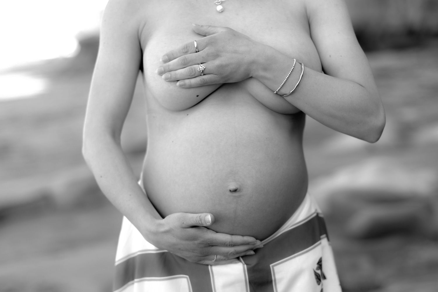 Black and white artistic photo highlighting a pregnant belly against soft lighting.