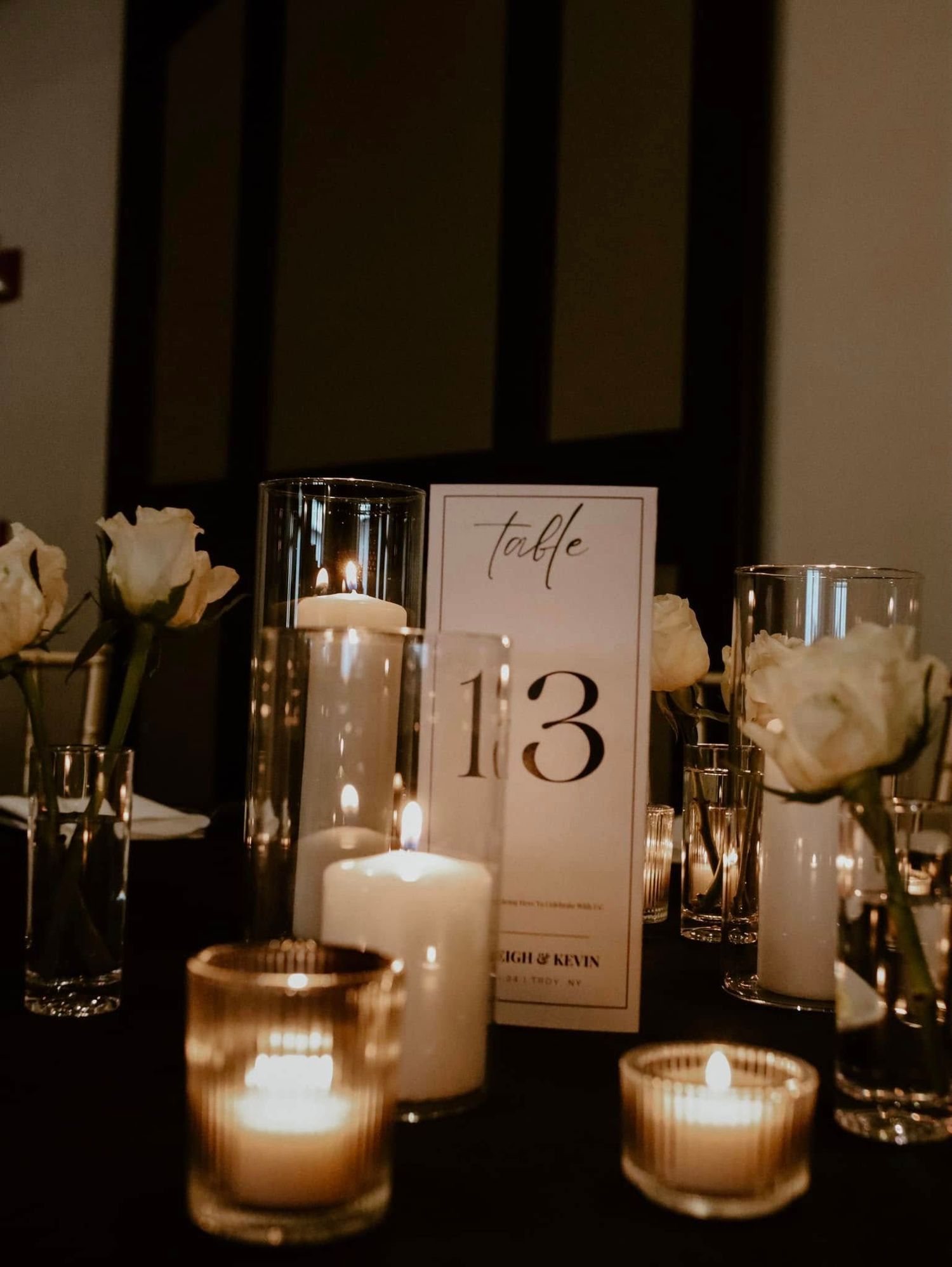 Rustic wedding setting with white roses, empty glasses and a "Just Married" note on a wooden barrel top.