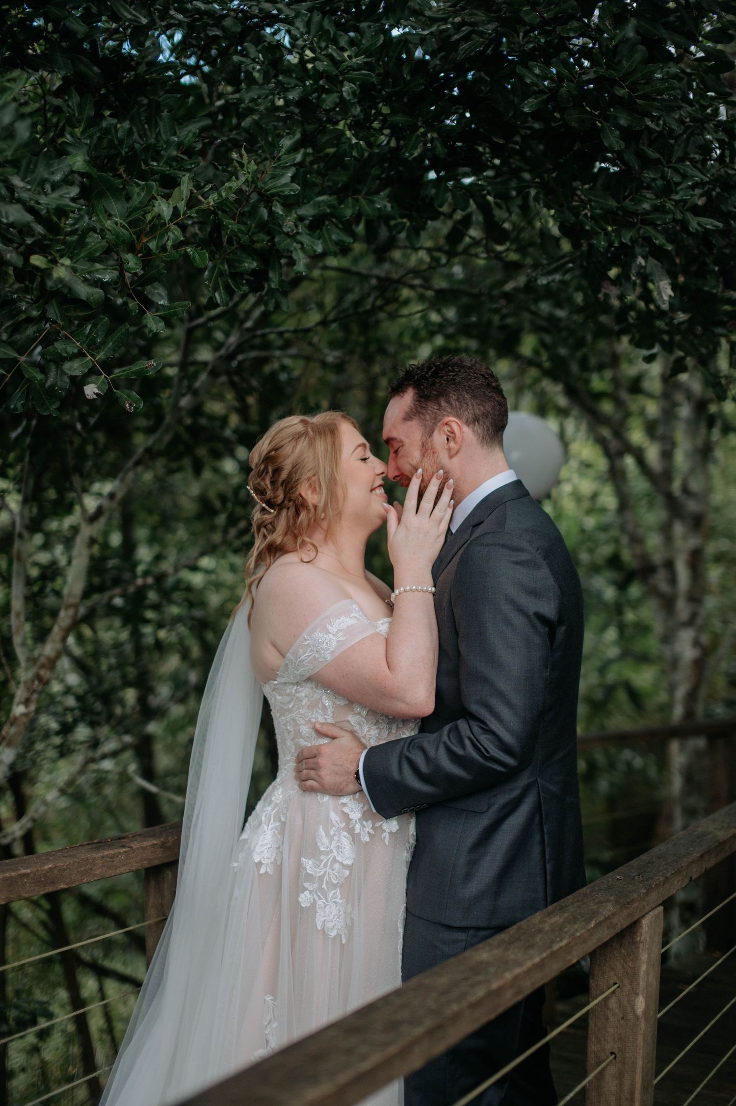 Intimate moment shared on wooden bridge surrounded by lush greenery.