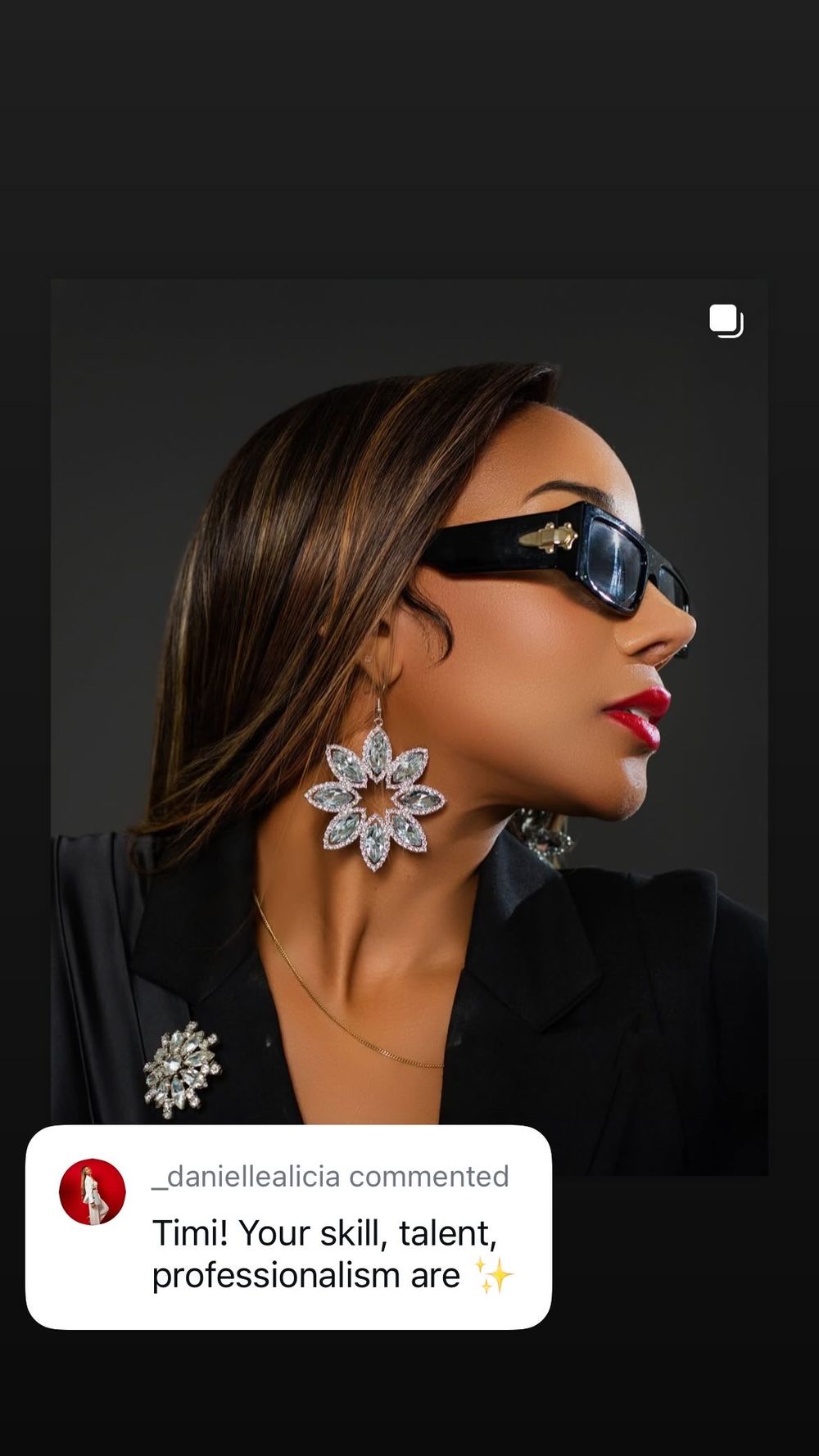 Fashion portrait featuring sleek sunglasses, bold red lipstick and statement crystal flower earrings against dark backdrop.