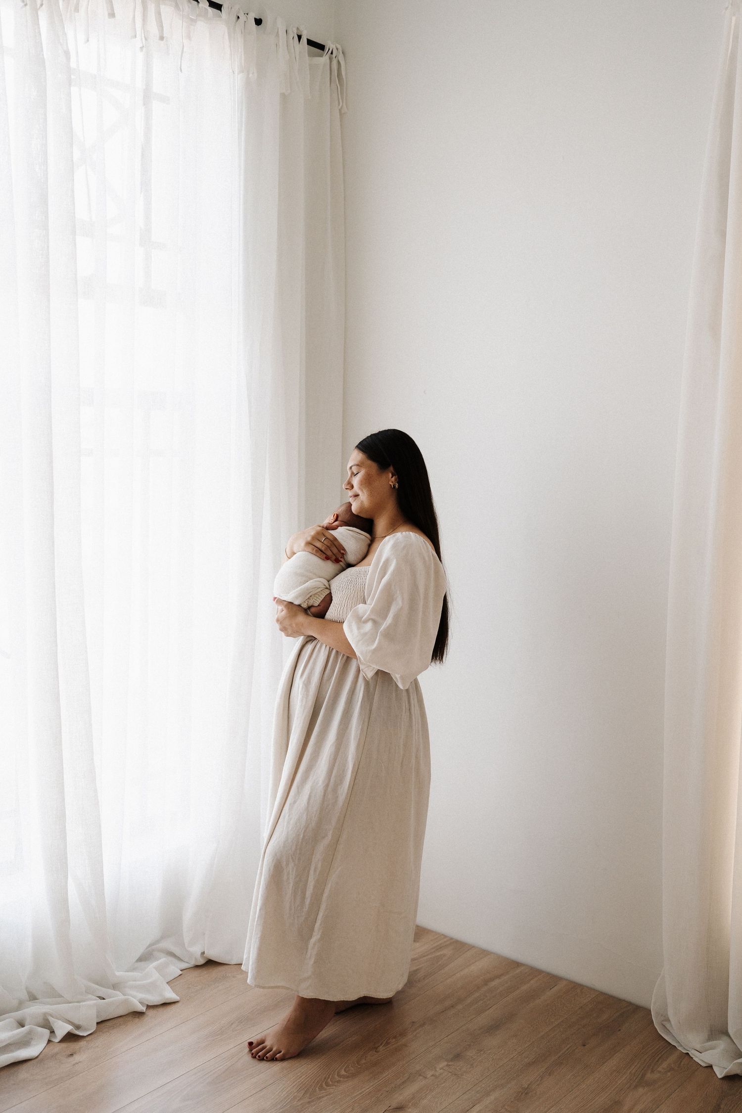 Minimalist pregnancy progression photos showing a white-dressed figure against light curtains and wooden floor.