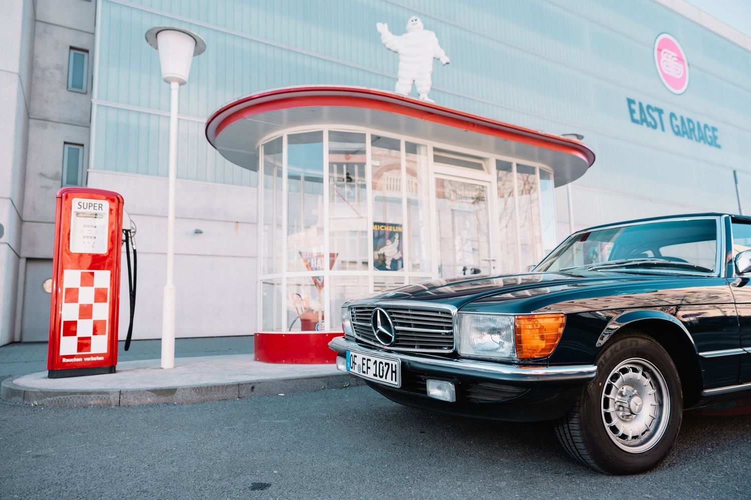 Gray Mercedes-Benz classic car sits parked outside a building with architectural columns visible in background.
