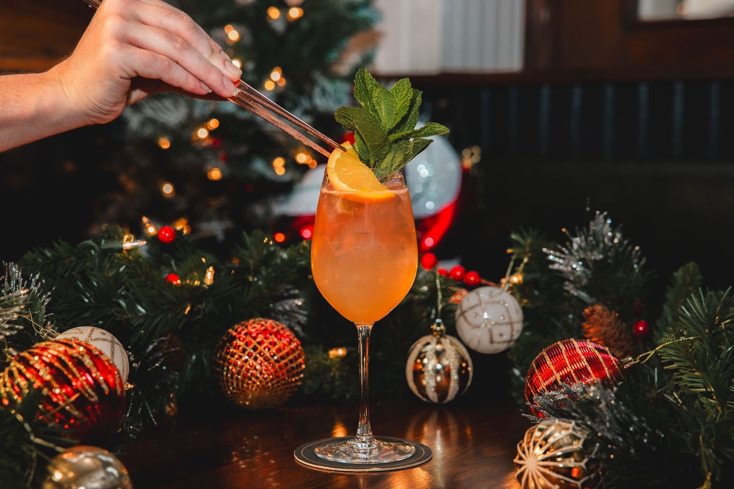 Festive holiday bar setup with illuminated cocktails and Christmas ornaments creating a warm ambiance.