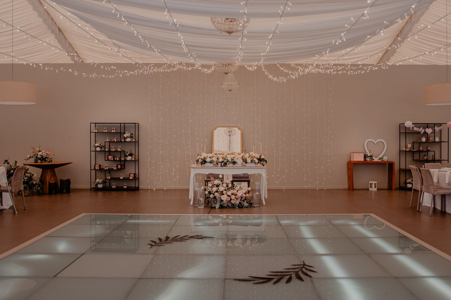 Large empty reception hall with white draped ceiling and decorative lighting.
