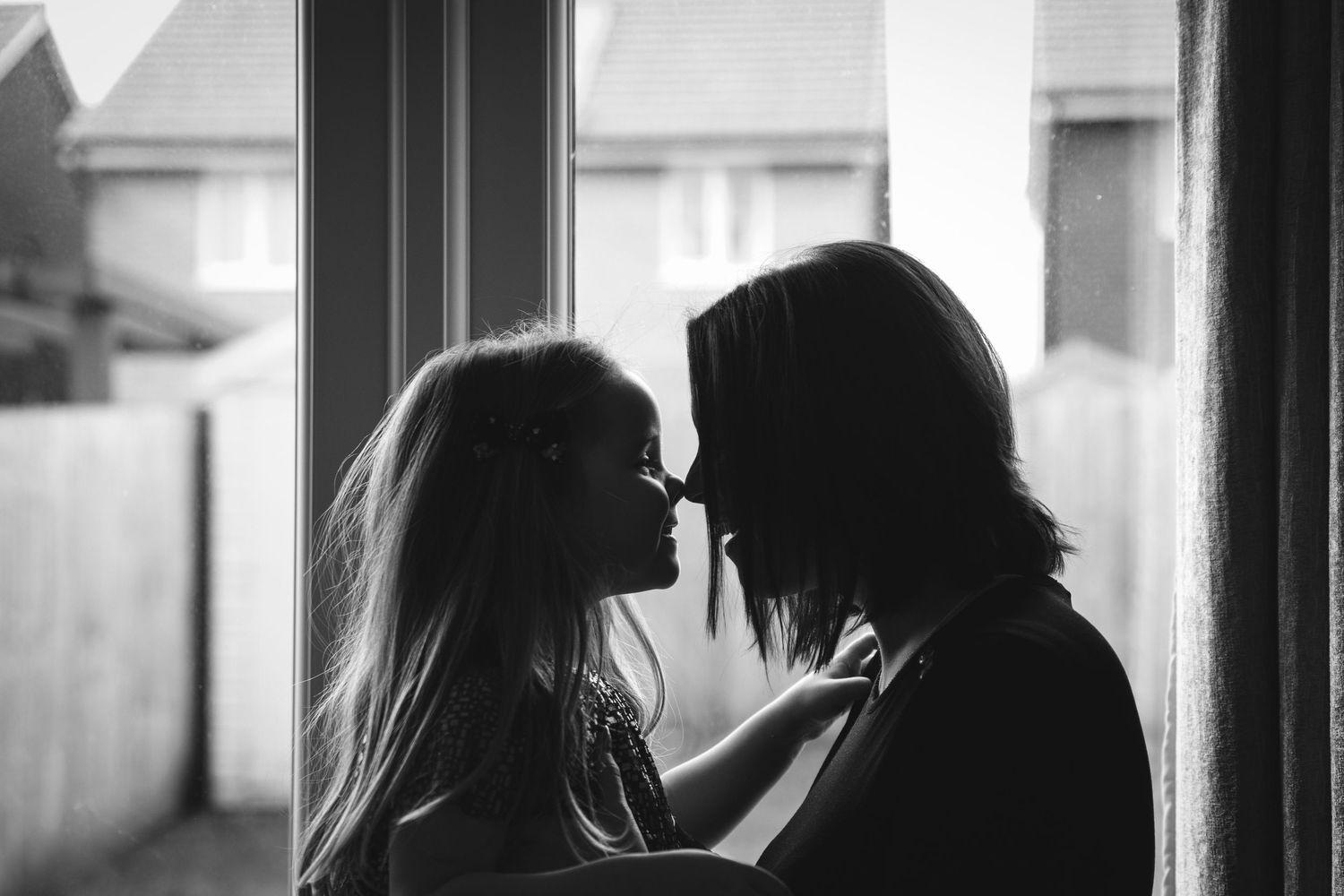 A romantic black and white silhouette of a couple near a window in an intimate moment.