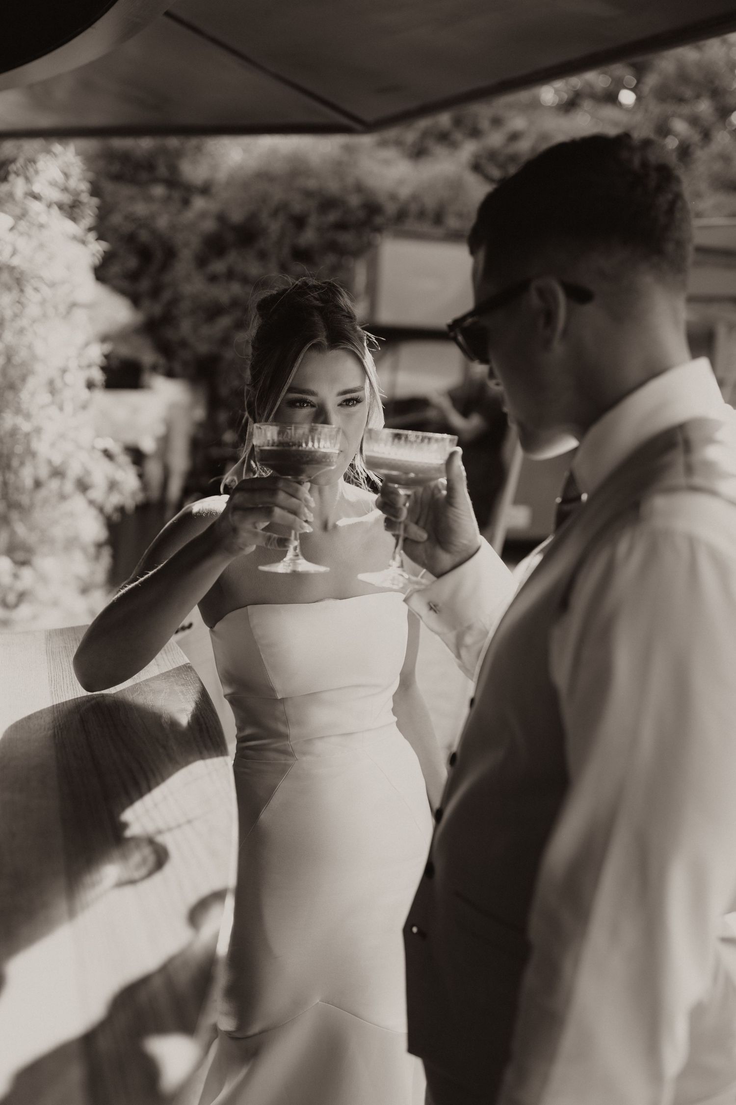A series of black and white photos showing wedding guests toasting and drinking champagne at an outdoor celebration.