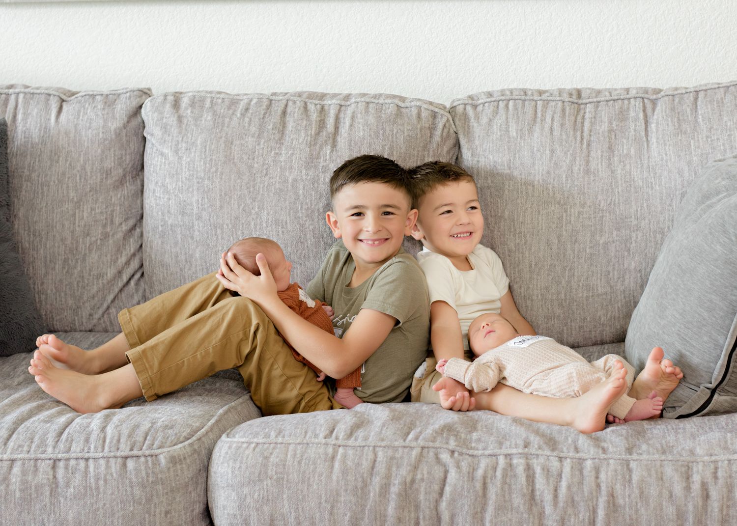 Young siblings sharing tender moment while relaxing on light gray couch.