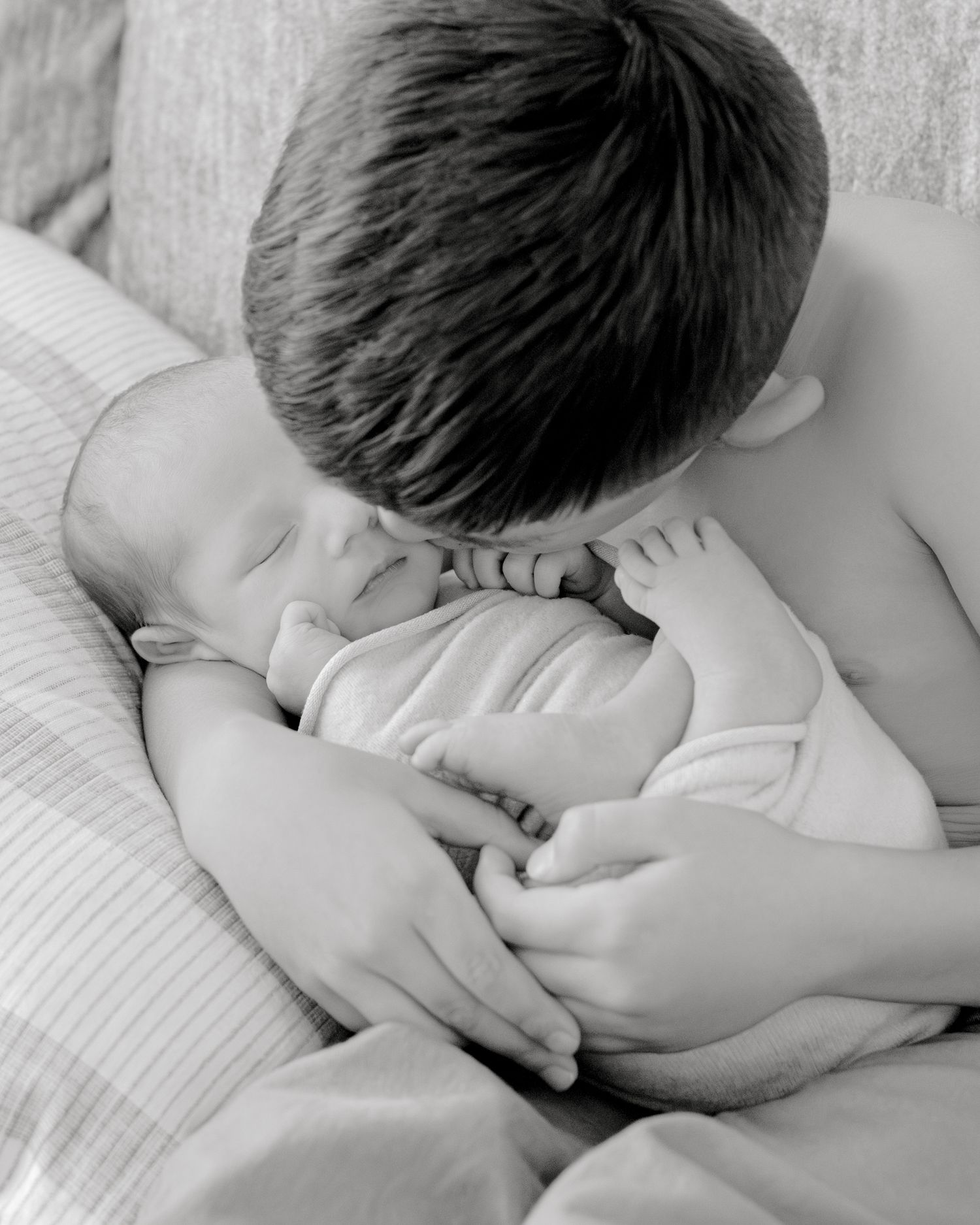 A series of black and white photographs showing a sleepy child laying down on white bedding.