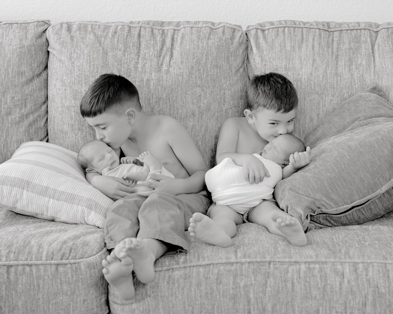A black and white photo sequence showing multiple stages of a sleeping baby changing positions in bed.