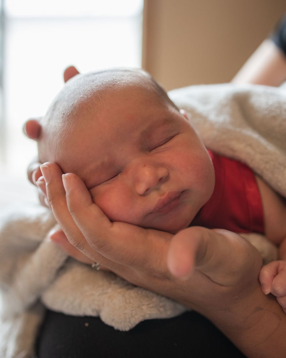 Five close-up images of a sleeping newborn baby wrapped in soft white blankets.