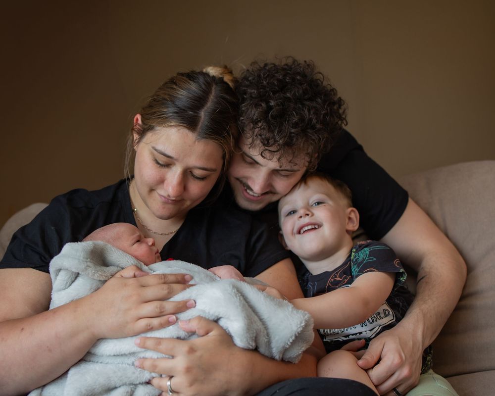 Family members snuggling close together on a couch in a tender intimate moment.