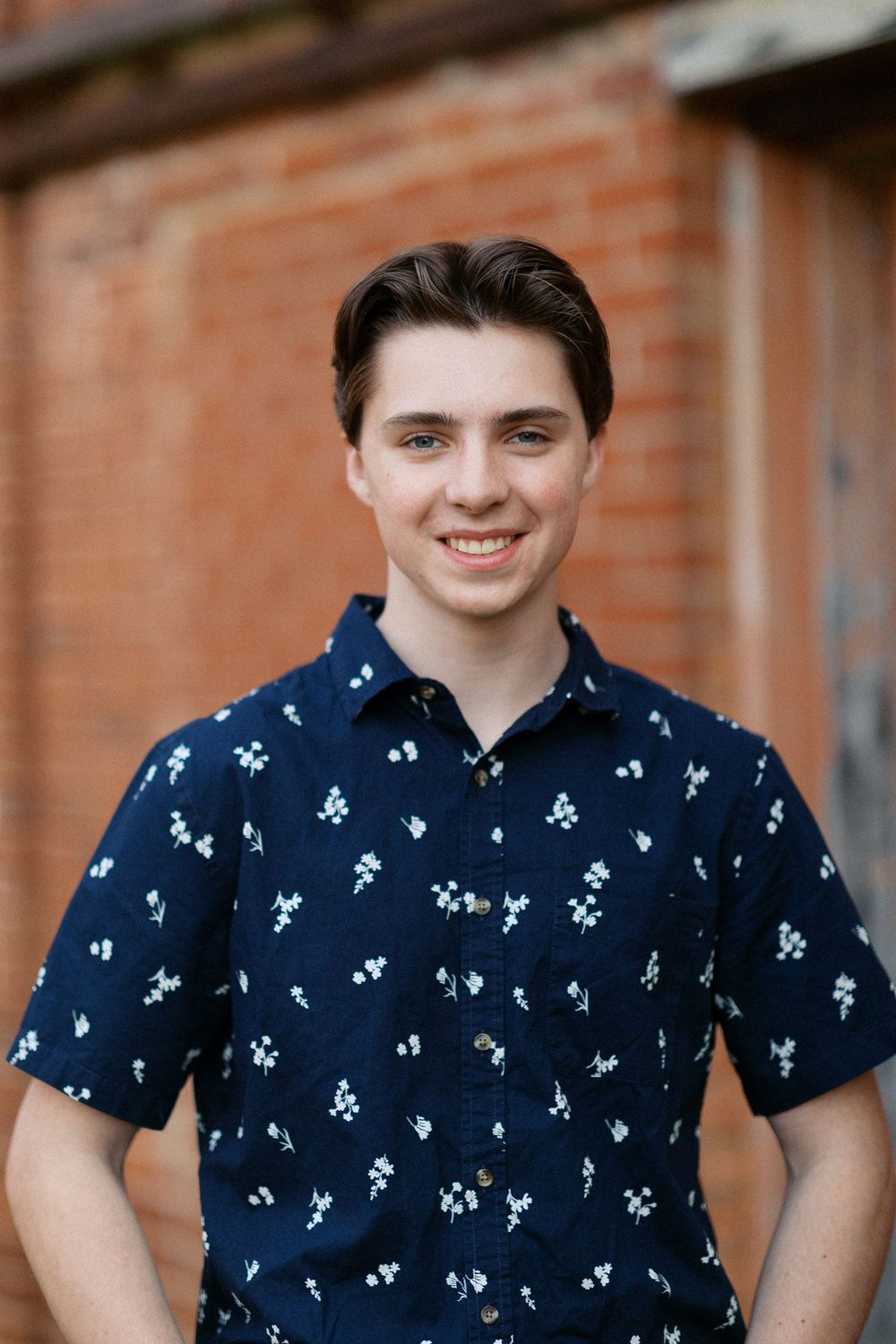 Close-up portrait sequence showing someone wearing a navy blue floral print short-sleeve shirt against a brick wall background.