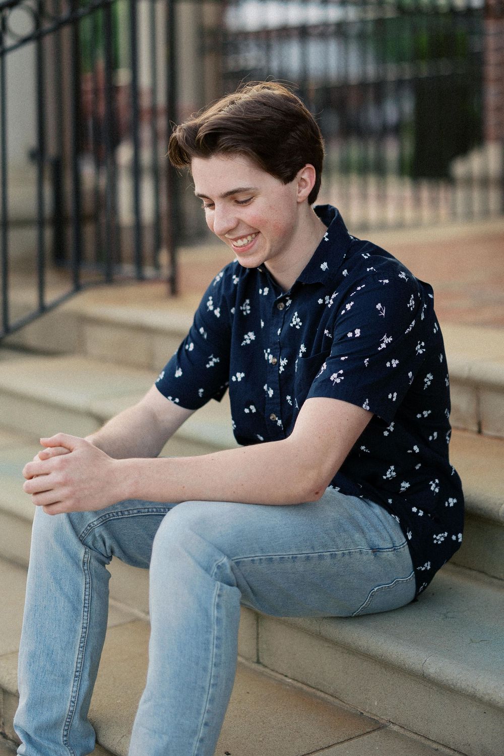 Casual seated poses on concrete steps showing person in blue patterned shirt and light denim jeans.