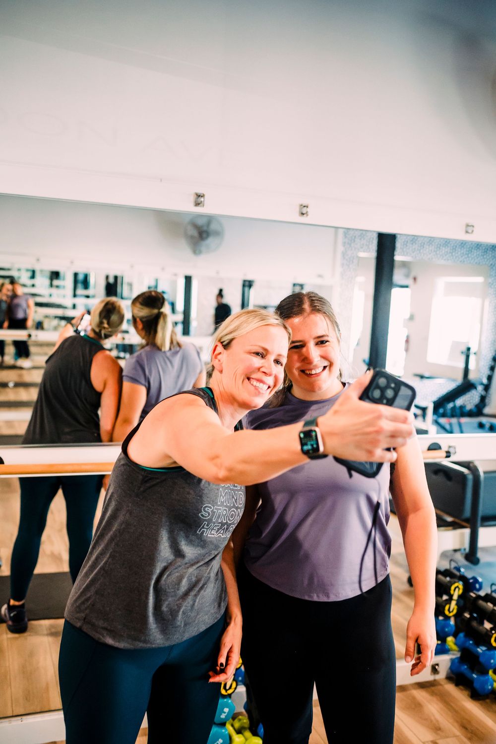 People taking a joyful selfie together after their workout session in a fitness studio.