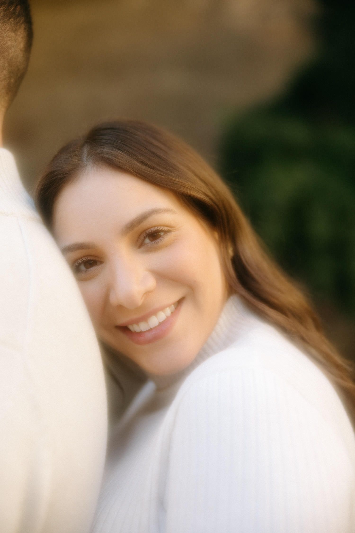 Soft focus close-up maternity portrait in white sweater.