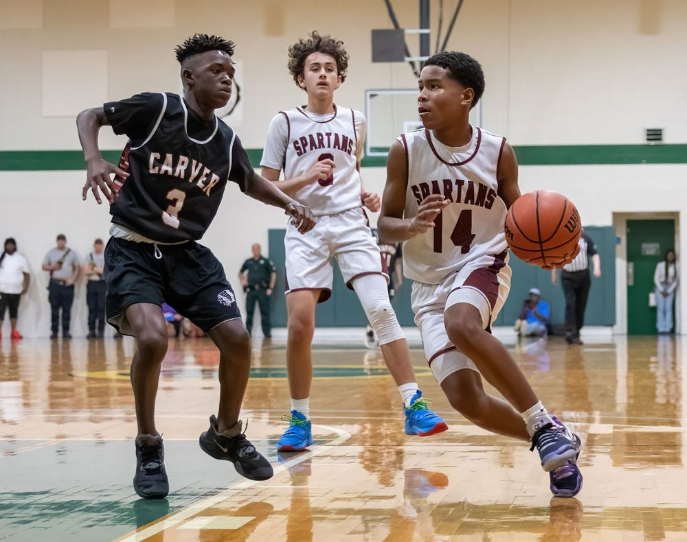 Basketball players compete in intense high school game with dynamic defensive moves.