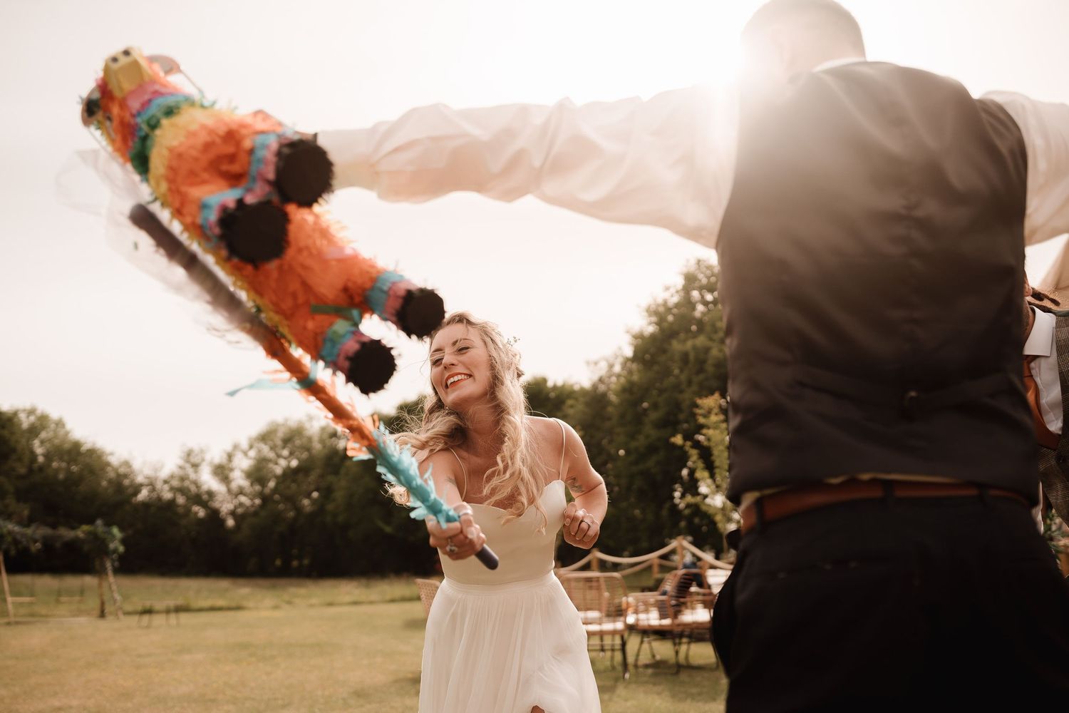 A cheerful couple having fun with colorful smoke grenades during an outdoor engagement photo session at sunset.