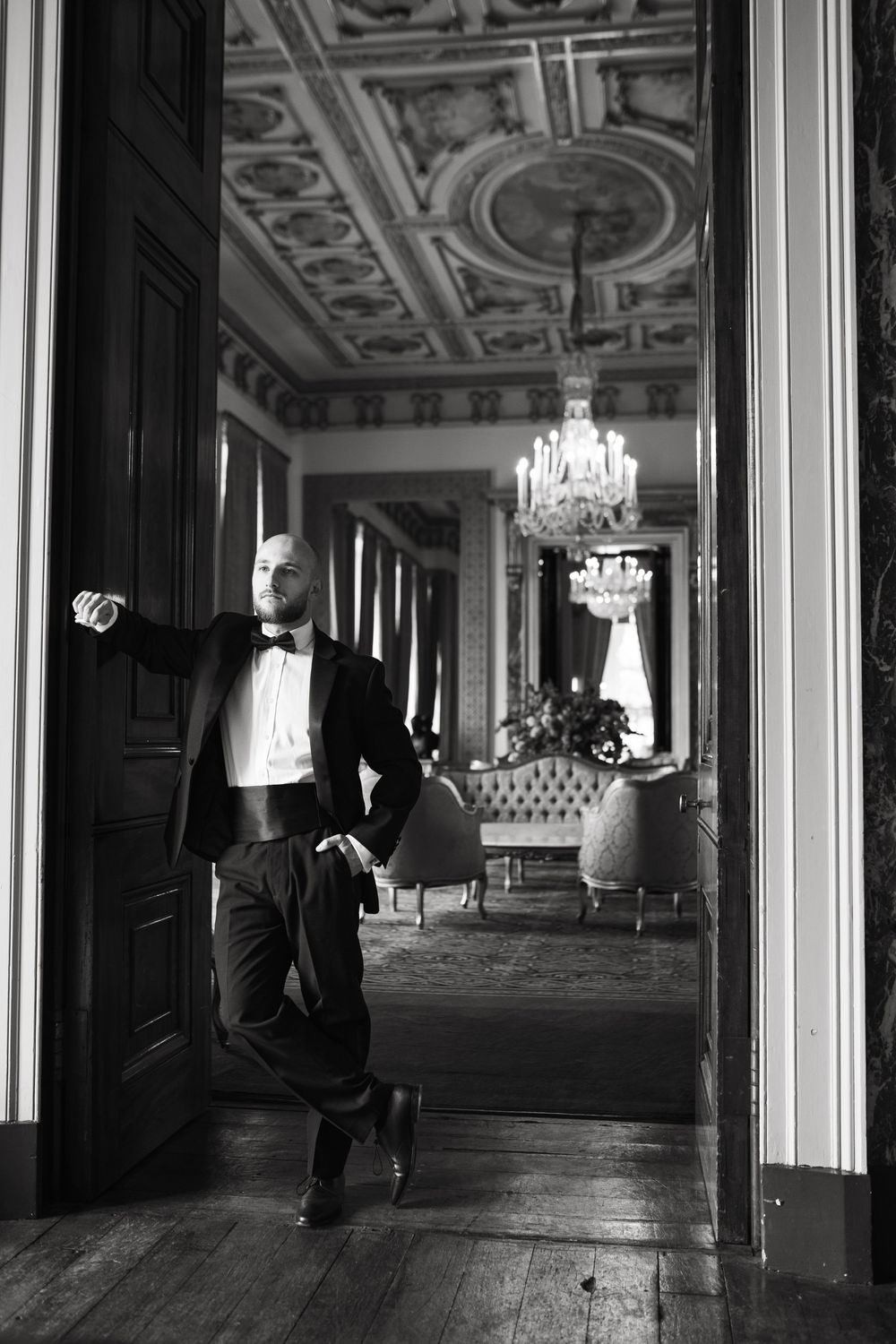 Fine art black and white photo series showing contrasting shadows and light in an ornate hallway with chandeliers.