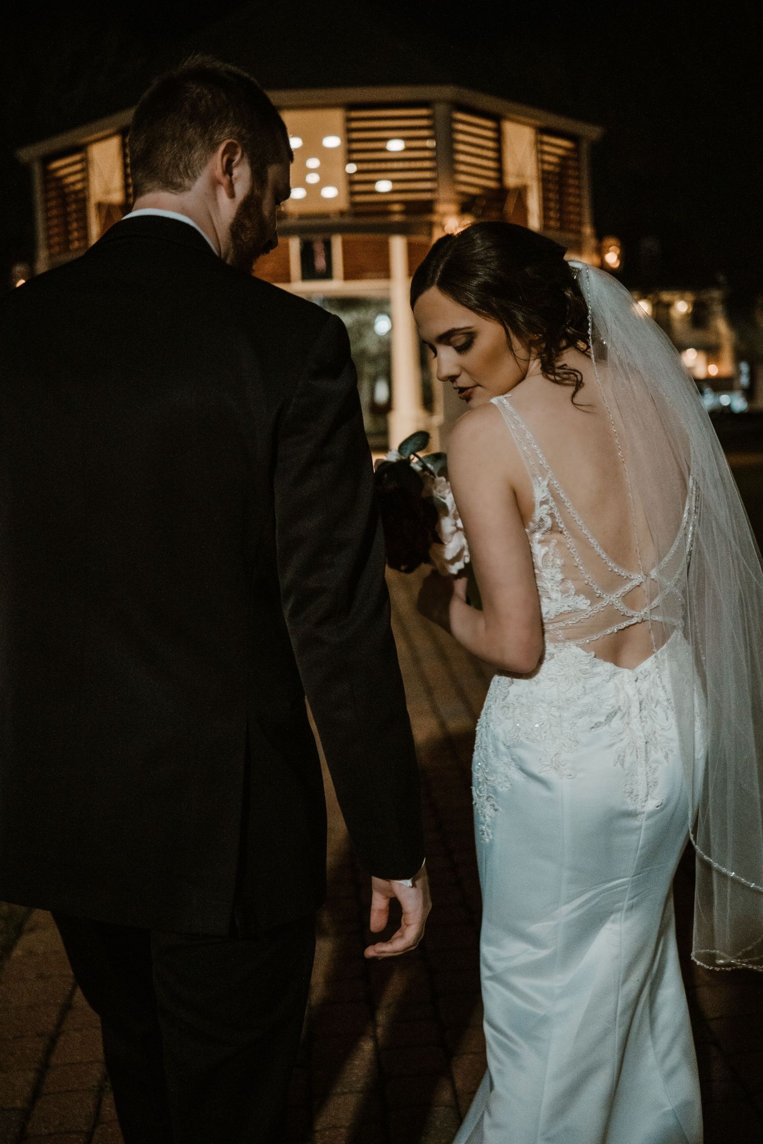 Bride in lace gown smiling under fairy lights at Lafayette wedding venue