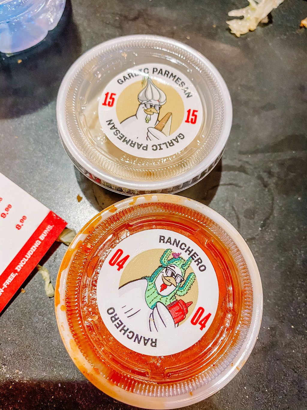 Two sauce containers with cartoon mascot logos displaying different flavor options.