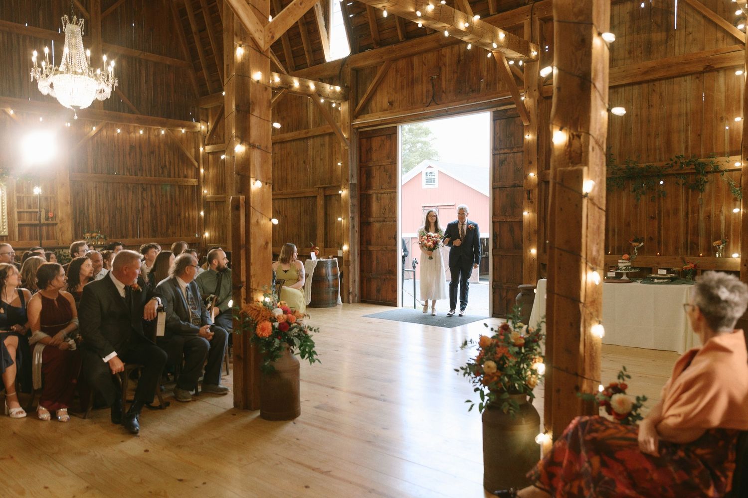 Elegant rustic wedding reception table with teal runner, floral centerpieces, and wooden barn wall backdrop.