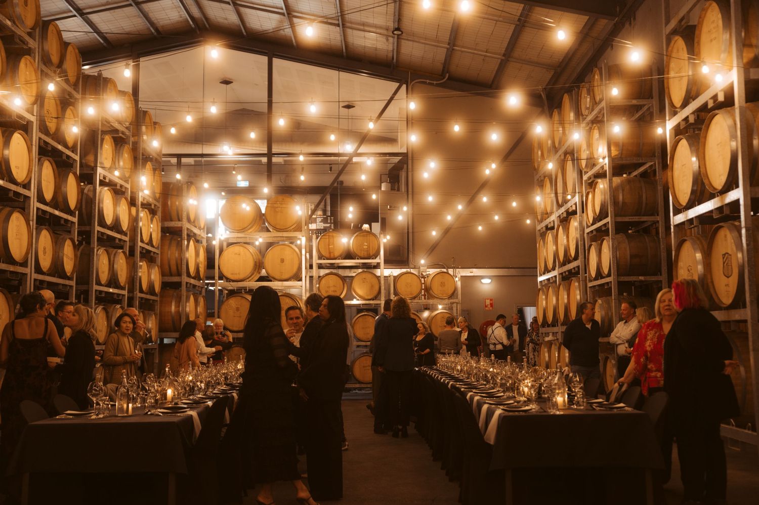 Corporate event dinner in wine barrel warehouse with festoon lighting - Yarra Valley event photography