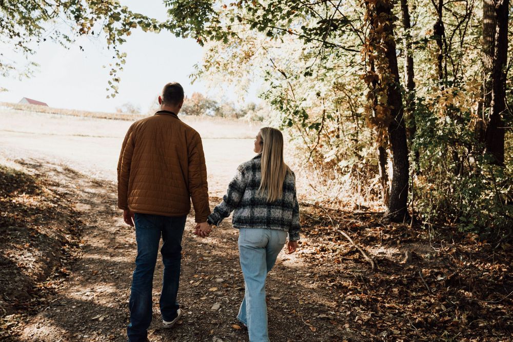 Couple walking together on forest trail during autumn afternoon.