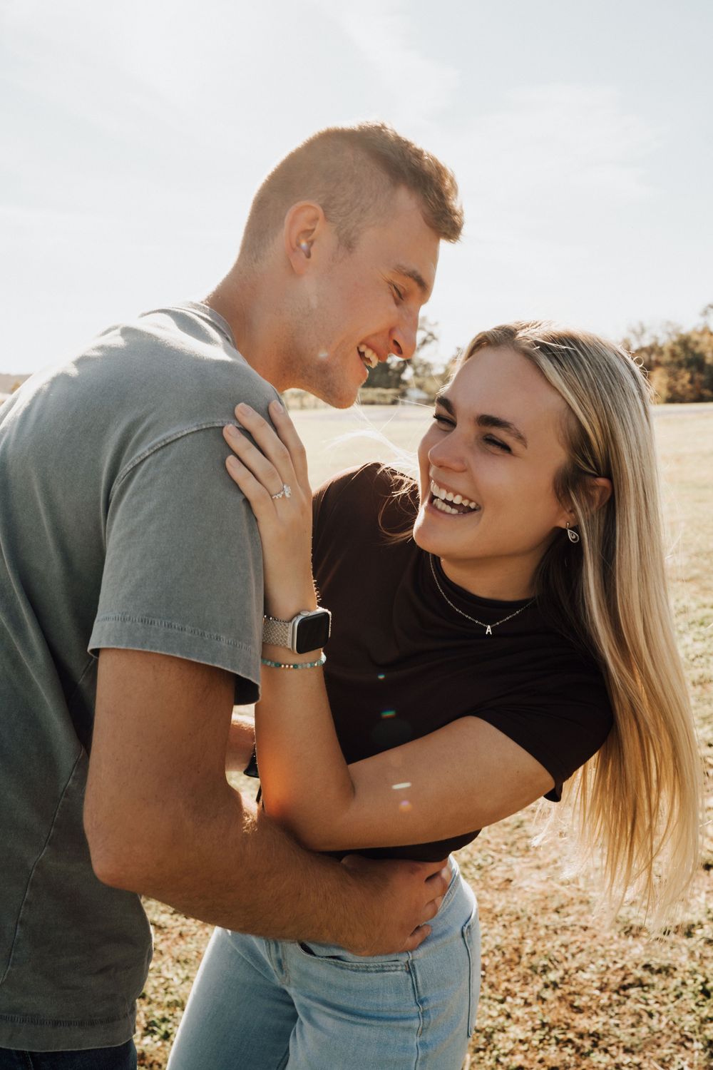 Joyful couple laughing together during a sunny outdoor photoshoot.