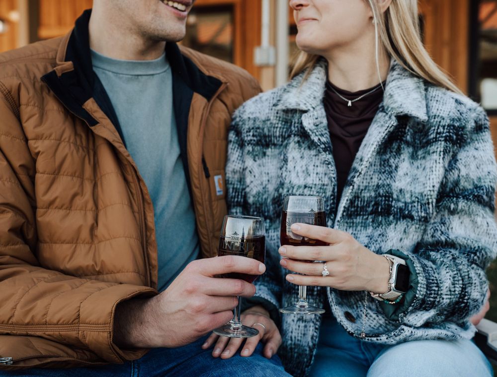 Close up of couple enjoying wine together in plaid and brown jackets.