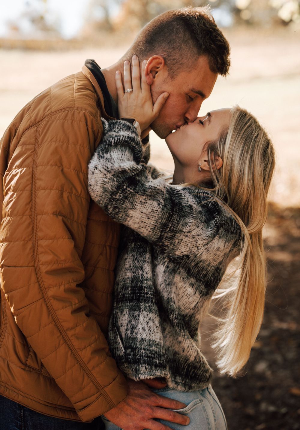 Romantic couple embracing and kissing while wearing matching winter sweaters.