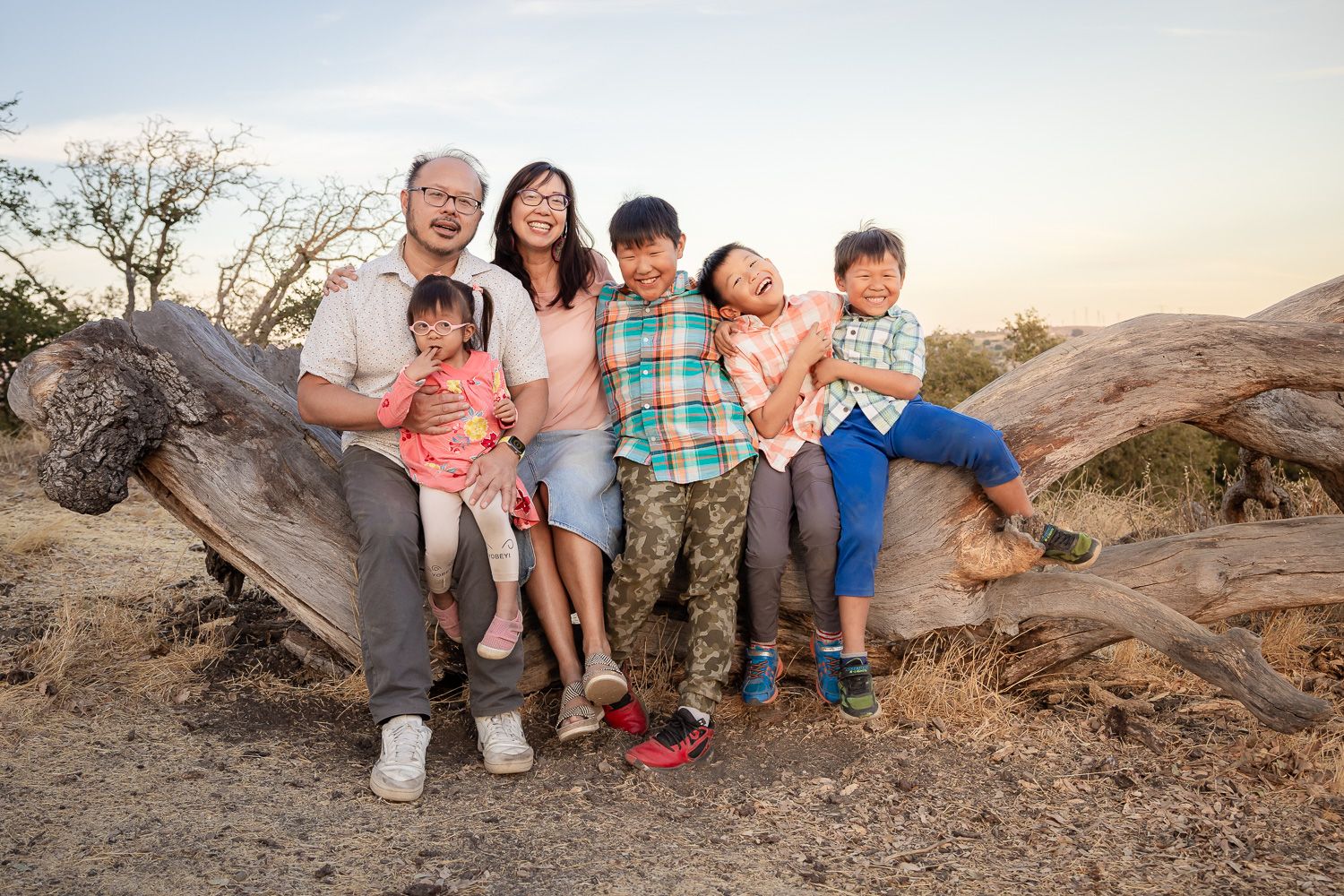 Family sits on tree log for their family photo session with Bay Area Photographer Cindy Tucey in San Jose