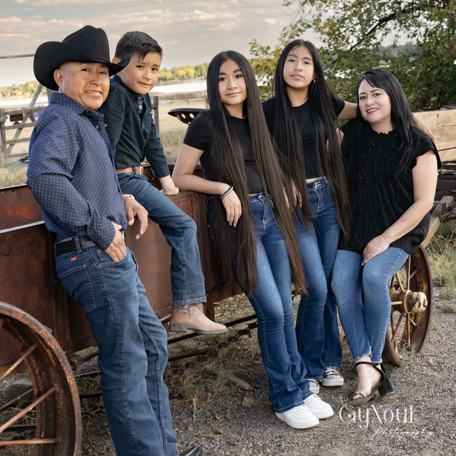 Family group posed on vintage wooden wagon in casual western wear.