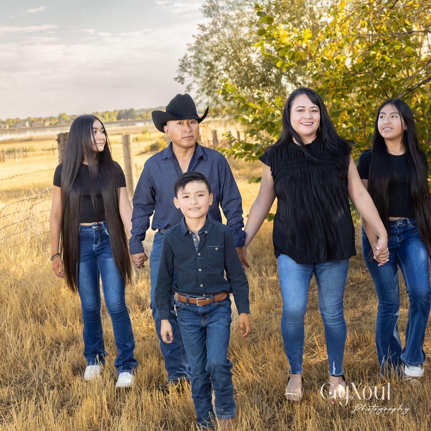 Family group standing together in field with golden sunset lighting.