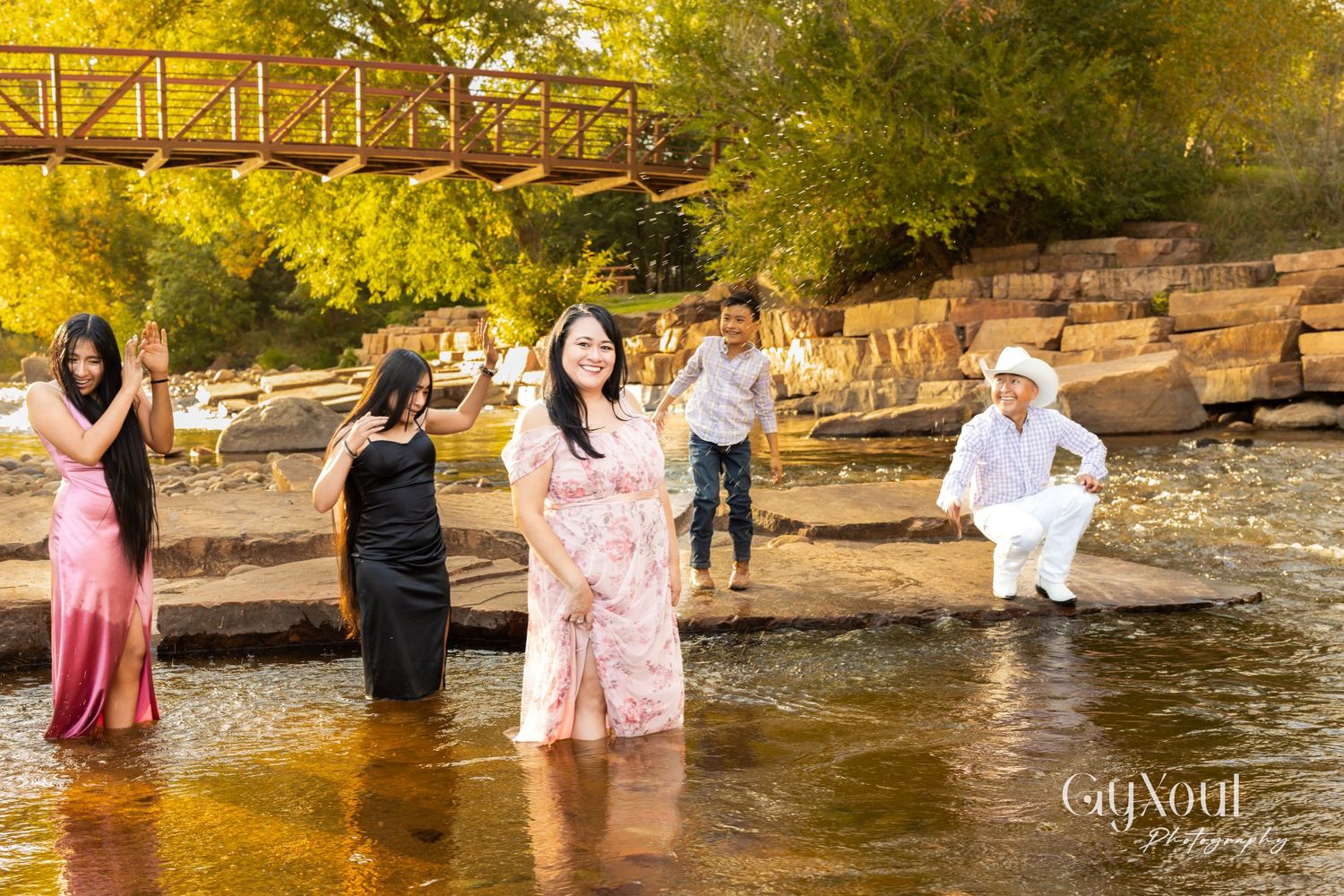 People splash and play in shallow river water on a sunny autumn day.