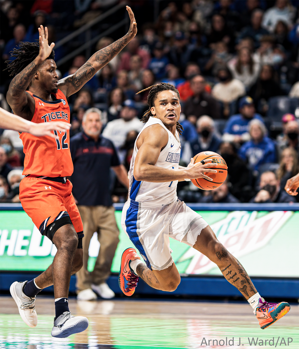 Basketball players in orange and white jerseys compete intensely during a fast-paced game.