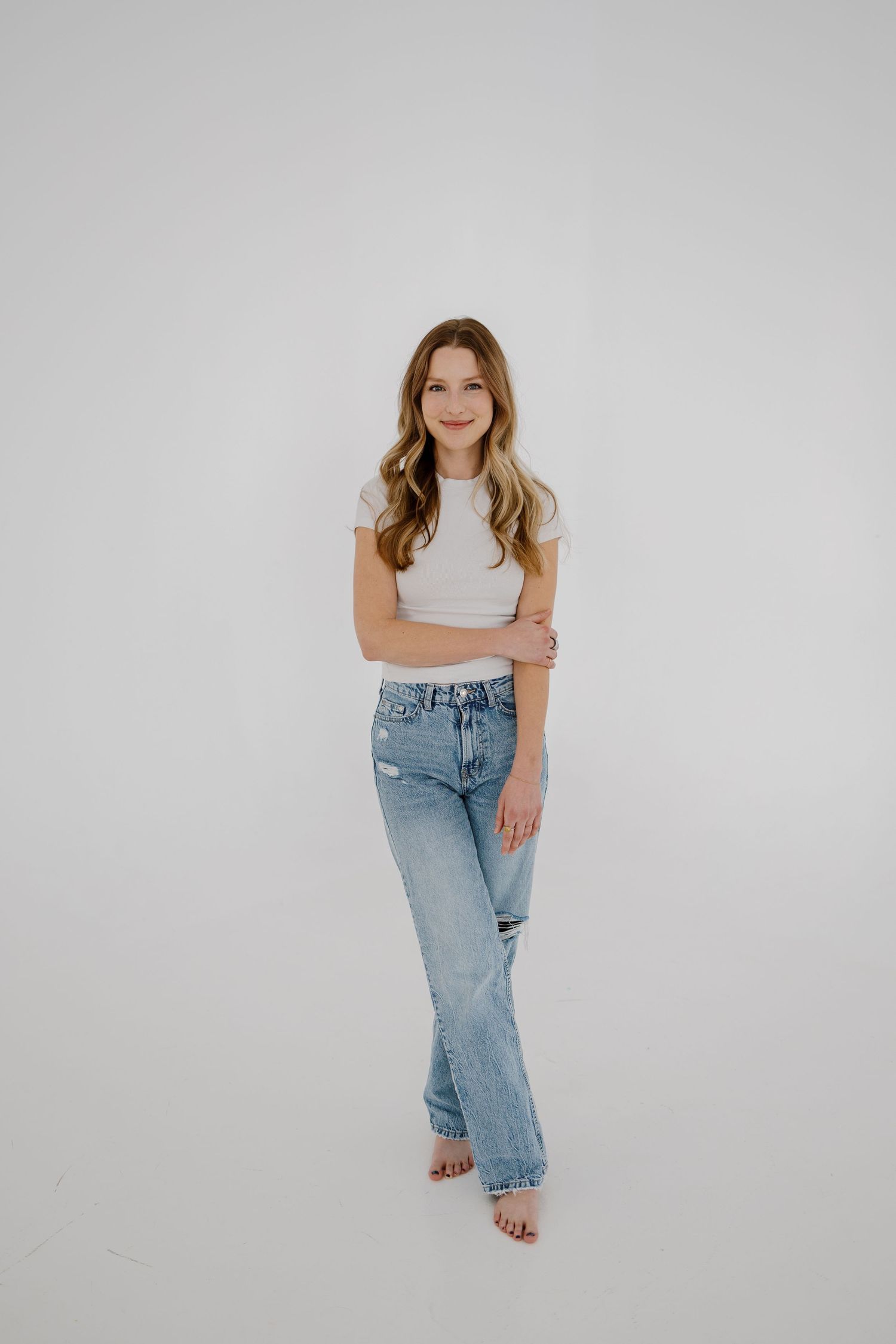 Casual portrait against white background wearing jeans and crop top.
