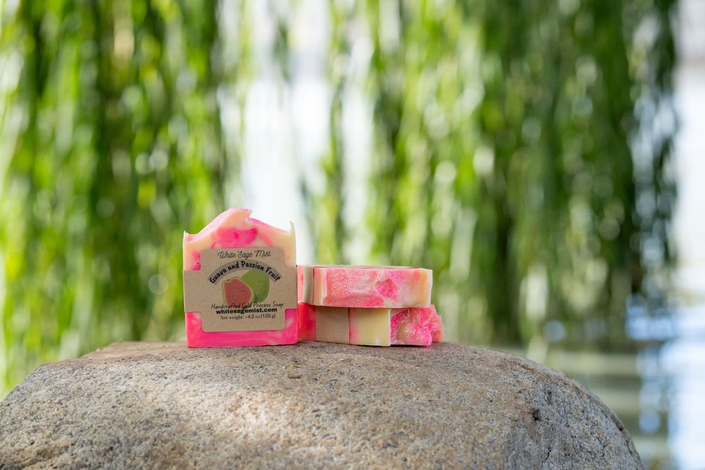 Pink handmade soap bars displayed on a natural stone with soft willow branches in the background.