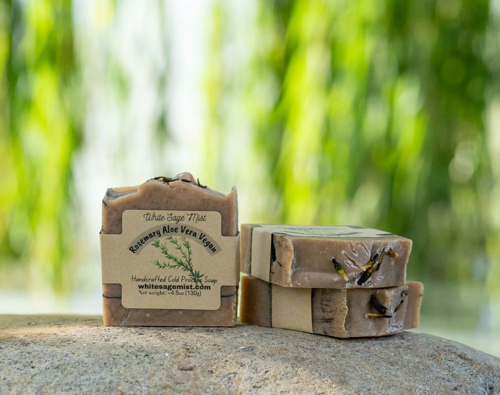 Natural brown handcrafted soap bars arranged on a rock with a blurred green garden background.
