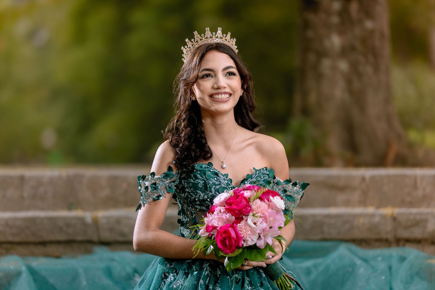 Elegant outdoor portrait session featuring emerald green dress and pink floral bouquet.