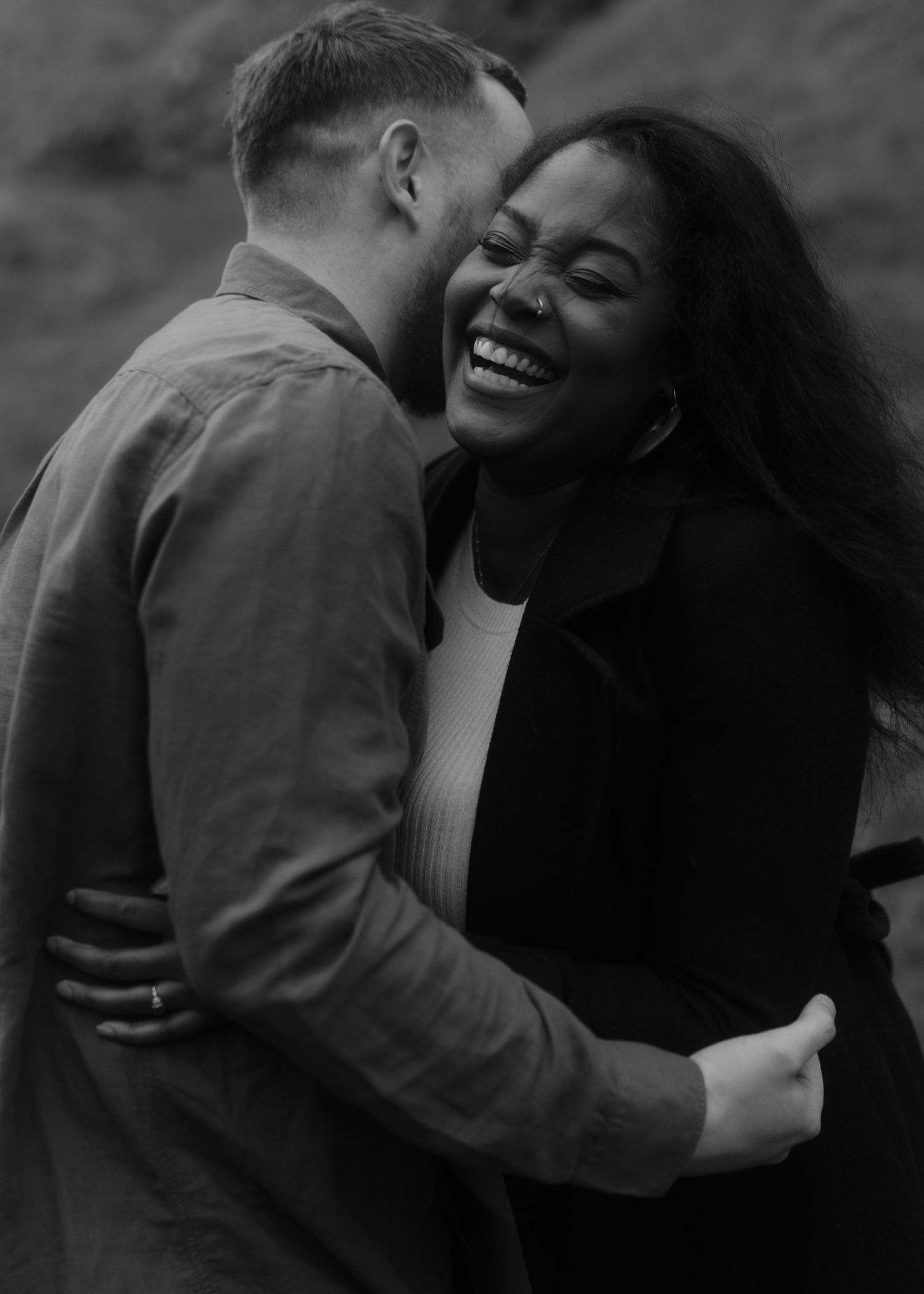 A candid black and white photograph of a happy couple sharing an intimate moment.