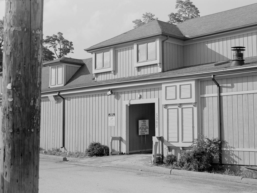 A large wooden barn-style building with vertical siding and a central doorway entrance in black and white photography.