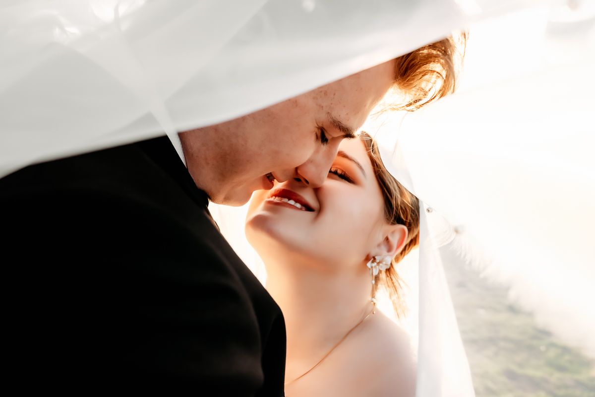 Intimate close-up portrait of wedding couple sharing tender moment against soft light.