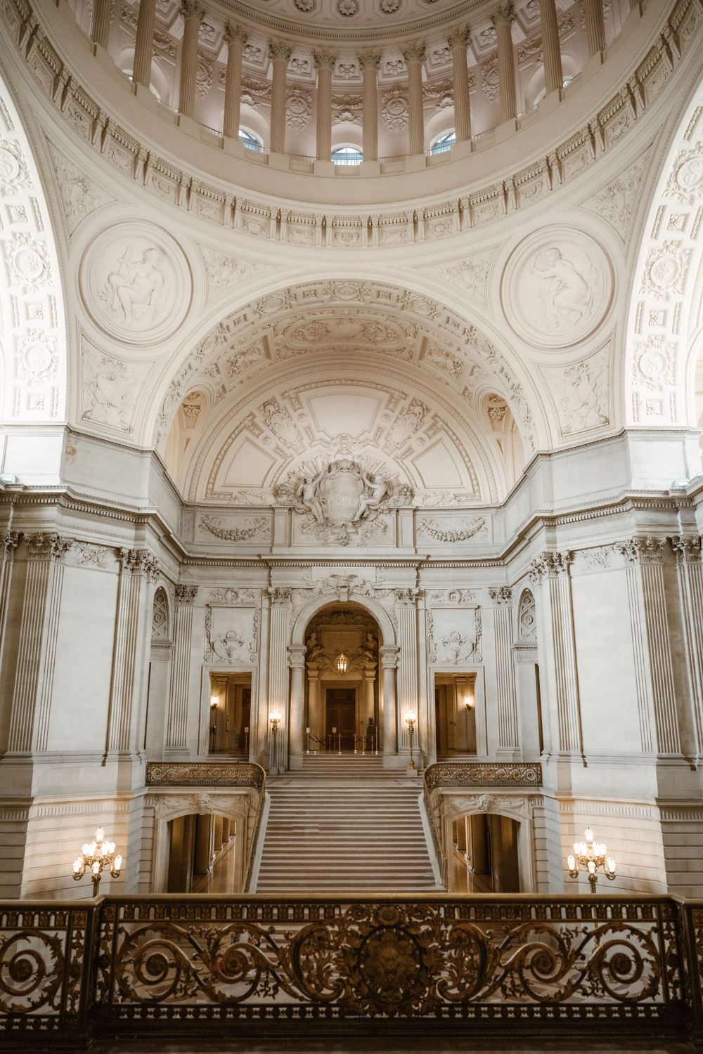 Majestic white marble interior of historic building with ornate ceiling and grand staircase.
