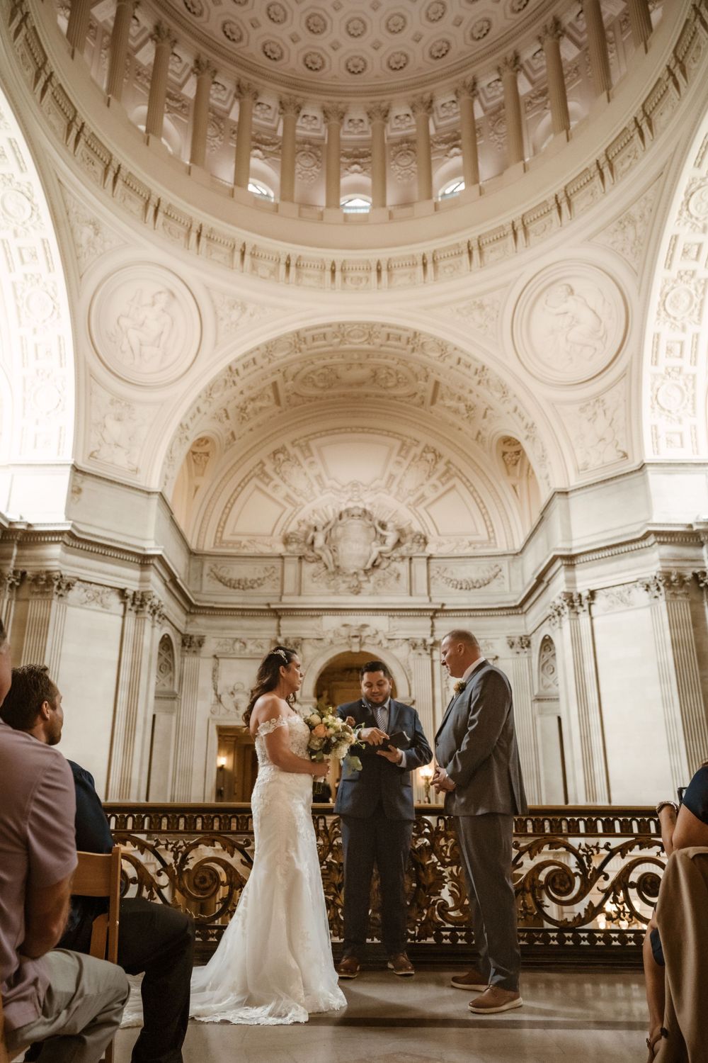 Wedding ceremony proceedings in grand marble hall with ornate dome ceiling.