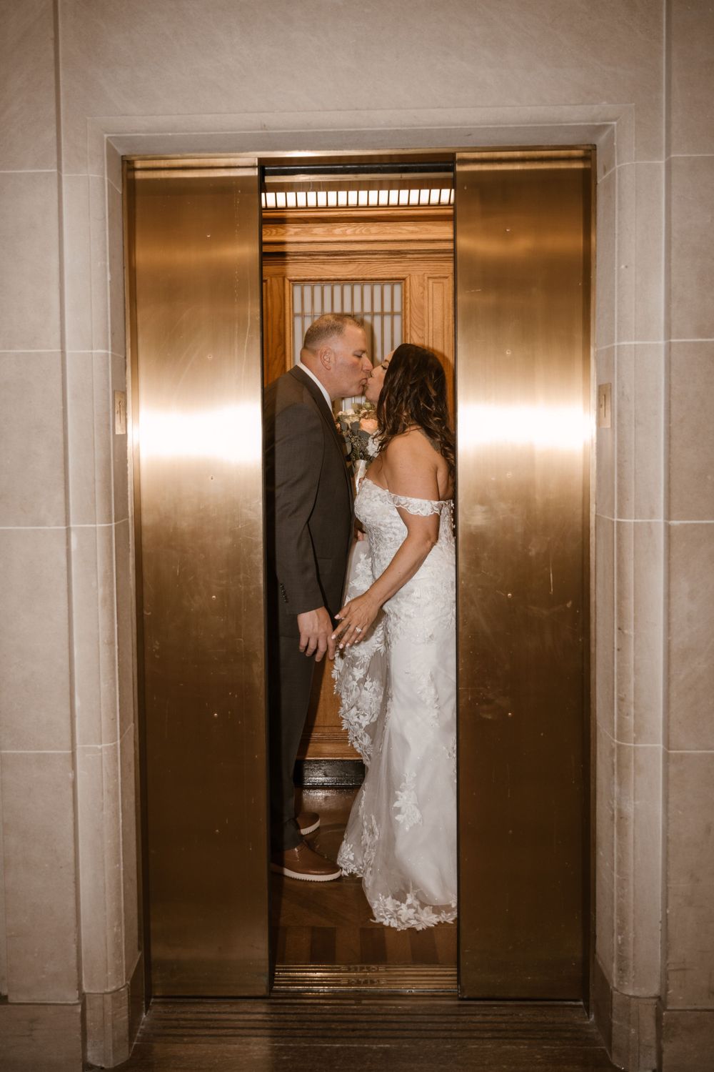 A romantic wedding moment captured in a golden elevator with the couple sharing an intimate moment.