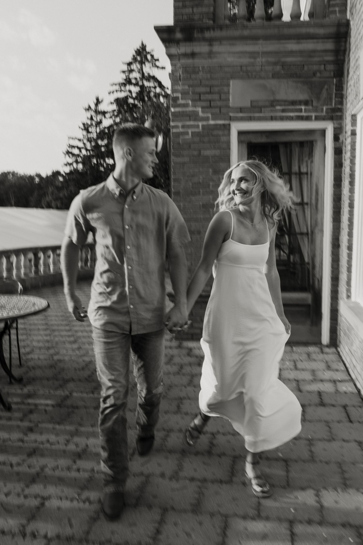 A black and white image showing a man and woman walking together on a brick path outside a building. Fort Worth Texas wedding photographer.