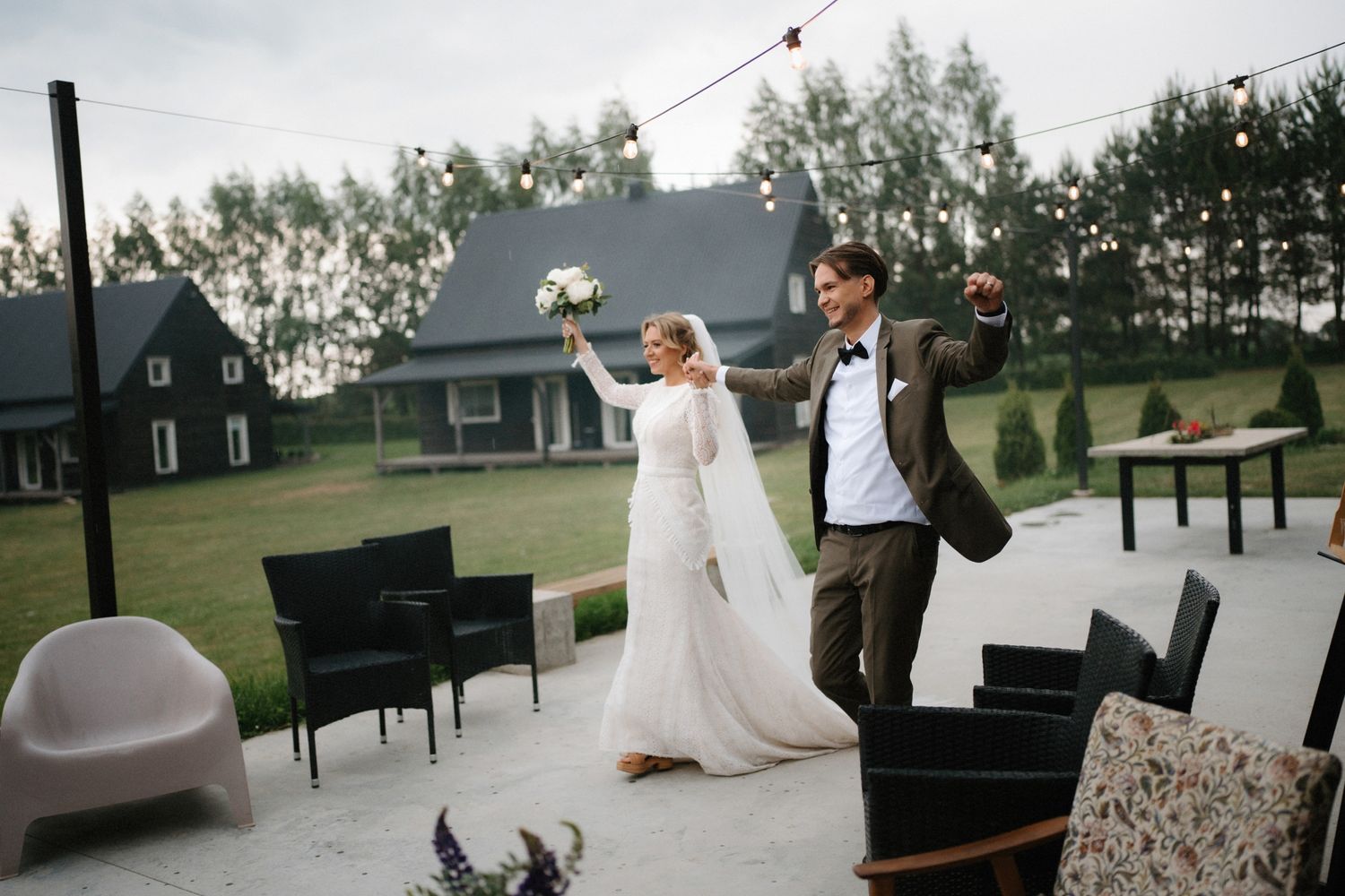 Outdoor wedding venue setup with string lights and rustic decor against a cloudy sky.